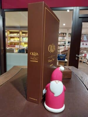 Porzellan-Weihnachtsmann steht im whisky & cigar salon vor dem geschlossenen Oliva Zigarren-Adventskalender.