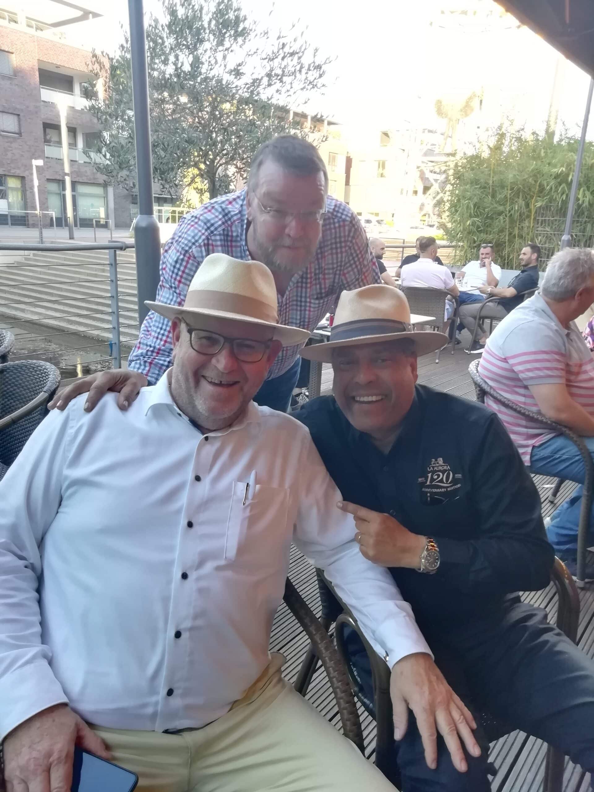 Manuel Inoa von La Aurora Cigars und Han Hilderink vom whisky & cigar salon sitzen auf der Terrasse und lachen.