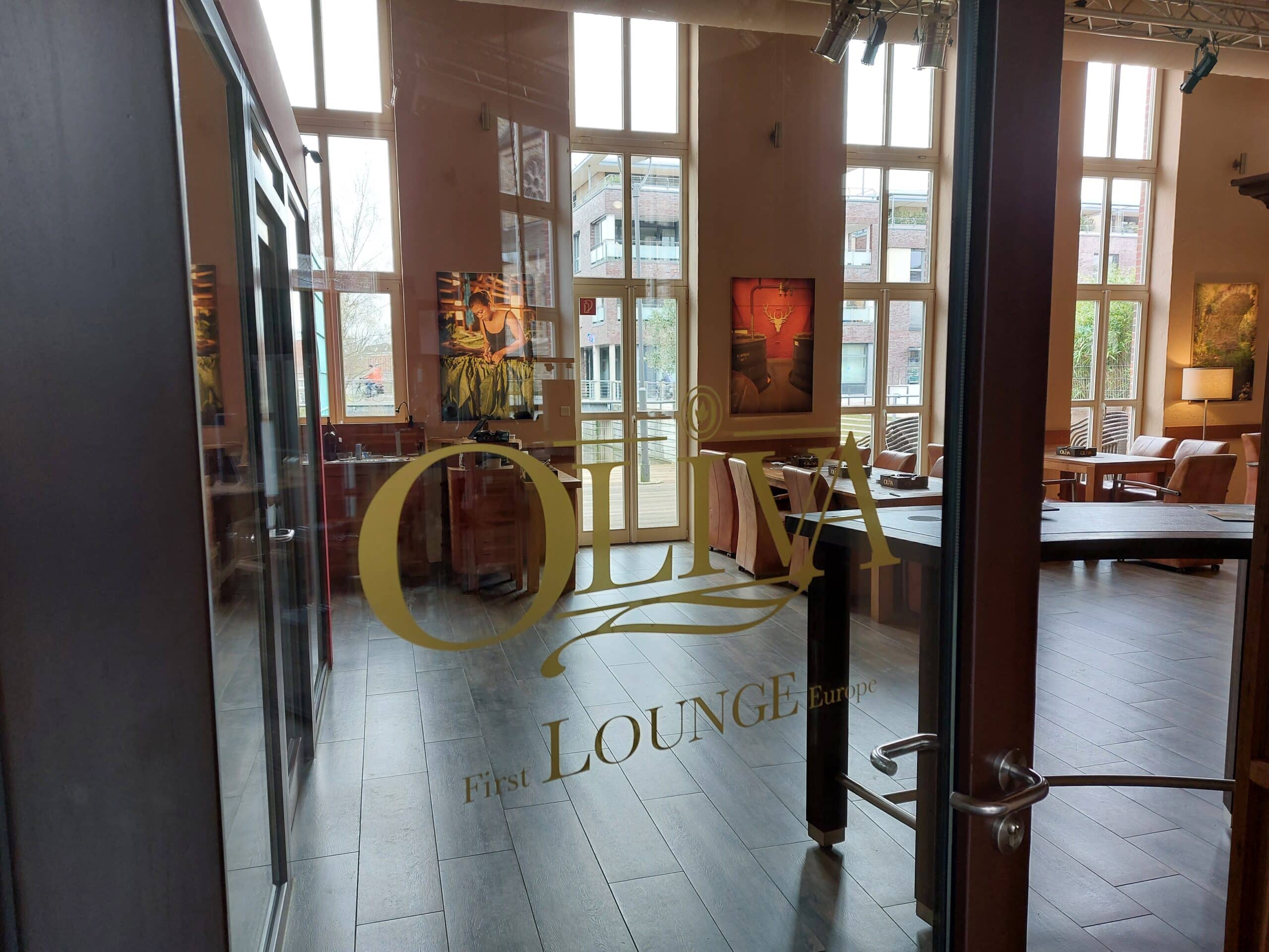 Blick durch die Tür mit dem goldenen Logo der Oliva Lounge im whisky & cigar salon.
