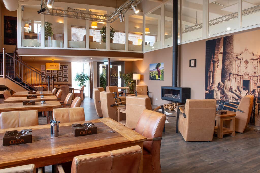 Blick in die Zigarren-Lounge des whisky & cigar salon, mit Tischen, Sesseln und Kamin.